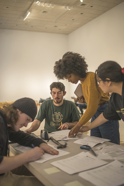 Cully Cuniff, Hampshire graphic design major, far left , And David Feather, Hot Springs, AR graphic design major, left, turns in their artwork in for the Grand Ball to Naja Garrette, San Antonio graphic design major, right and Karisma Danas, Richmond drawing major, far right, at the Dishman Art Museum, Tuesday. UP photo by Noah Dawlearn