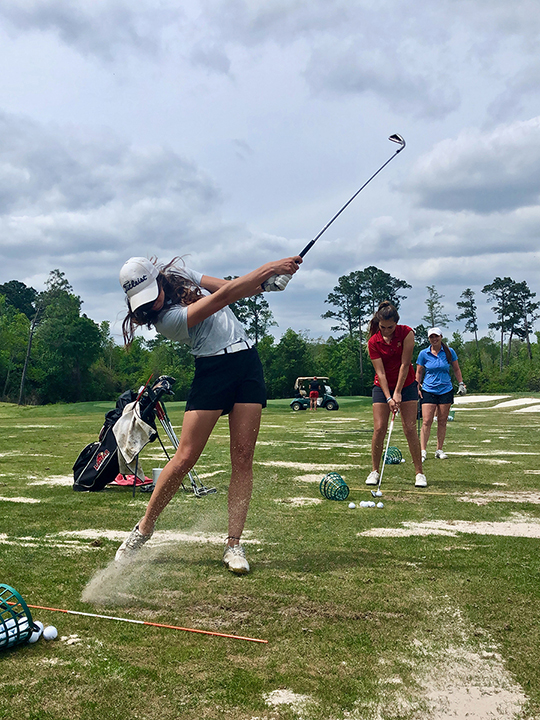 Madilyn Smith, left, Laura Pasalodos-Barcelo and Brooke Duzan practice their golf swing at the Beaumont Country Club, March 29. UP photo by Vy Nguyen