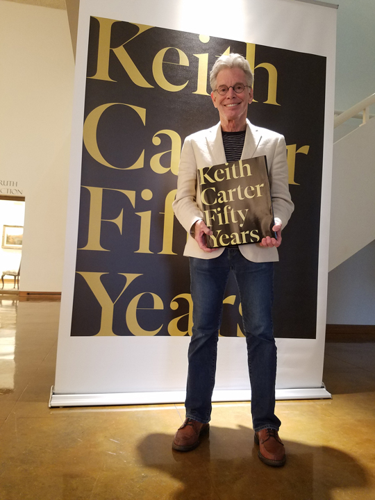 Keith Carter stands with a copy of his retrospective book in the Dishman Art Museum, which is hosting an exhibition of the same name. UP photo by Sierra Kondos