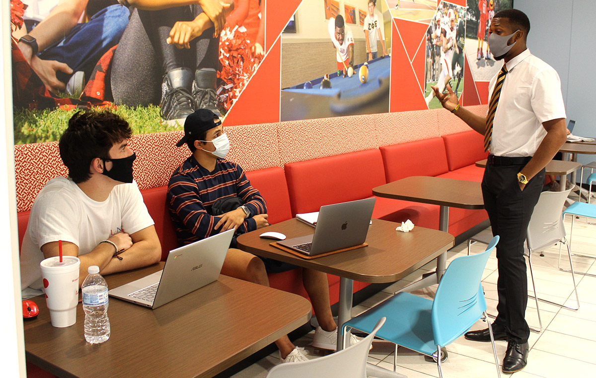 SGA president Trevion Wilson, right, speaks to students James Farmer, Mont Belvieu freshman, far left, and Justin Ramirez, Mont Belvieu freshman, center, about SGA's upcoming projects in the Setzer Center, Oct. 14. UP photo by Olivia Malick