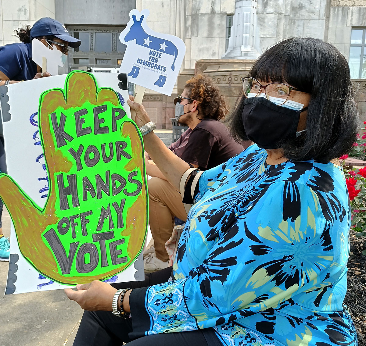 Rally attendees hold signs in protest of voter suppression, April 28. UP photo by Sierra Kondos