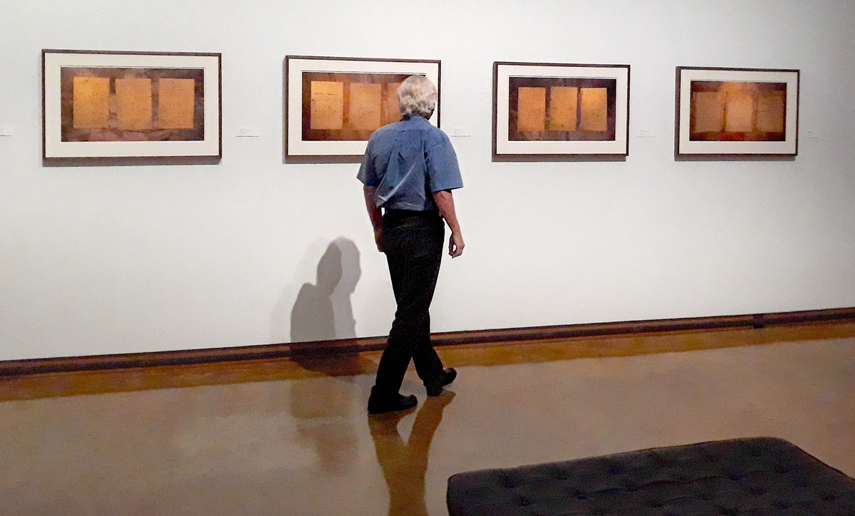Dishman Art Museum curator Dennis Kiel inspects work by Keith Carter at the Art Faculty Exhibition, which is on display through Sept. 11. UP photo by Madalyn Blackshear