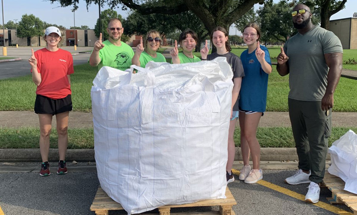 On the first recycling drop-off day, student and faculty volunteers hold up 'No. 1' to celebrate the first full bag of recyclables collected. Courtesy photo