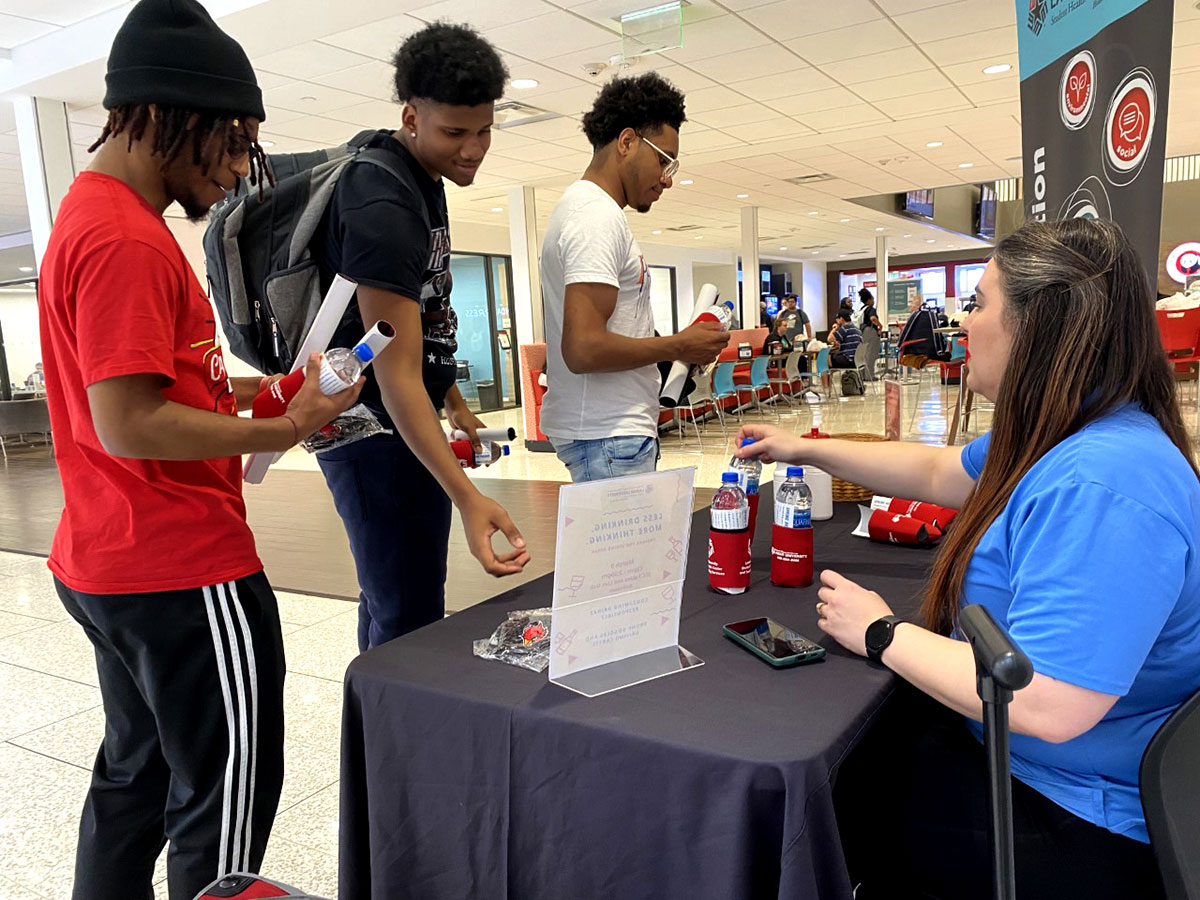Braiden Clark, Beaumont freshman, Johnny Morris, Dallas freshman, and Robert Southwell, Jasper freshman receive handouts and free water bottles at the Wellness Wednesday for alcohol safety at the Setzer Student Center, March 2. UP photo by Maddie Sims.