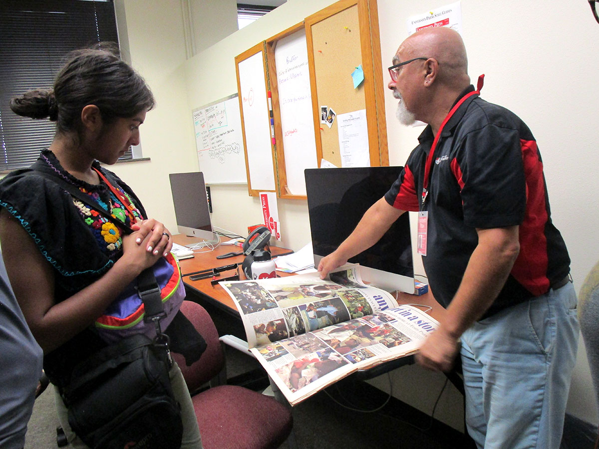 Hailey Deeds (left) talks with Andy Coughlan over old newspaper coverings of hurricane recovery. UP photo by Maddie Sims.