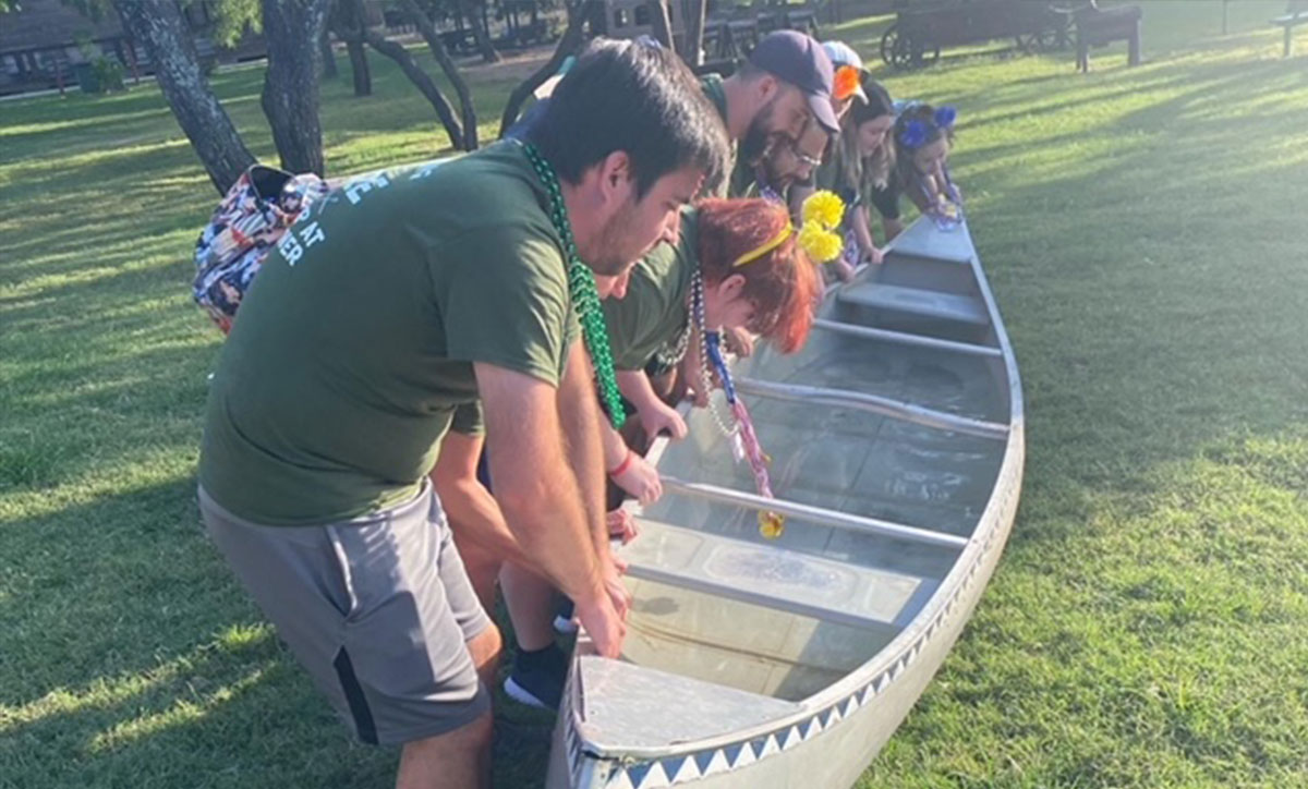 A group of students help dump out water and ice from a canoe at camp Buckner during one of the previous semesters.