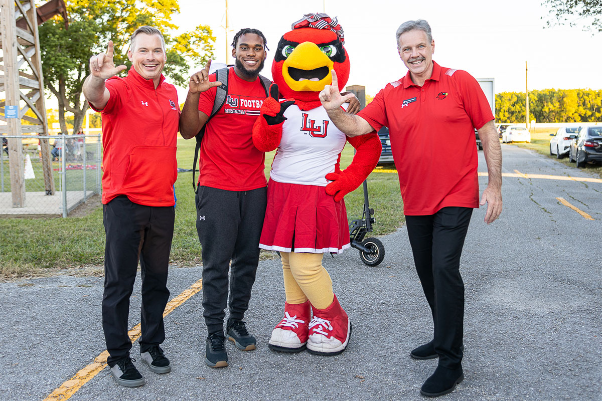 Football coach Blane Morgan, left, Tyler Jackson, Lu, and President Jaime Taylor flash the “L” sign at the Homecoming bonfire and pep rally, at the Spindletop-Gladys City Field, Sept. 30. UP photo by Brian Quijada.