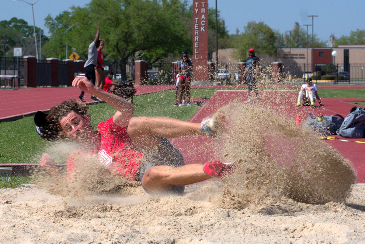 Freshman Trevor Fernandez lands in the sand while practicing jumps at Ty Tyrell Track, April 8.