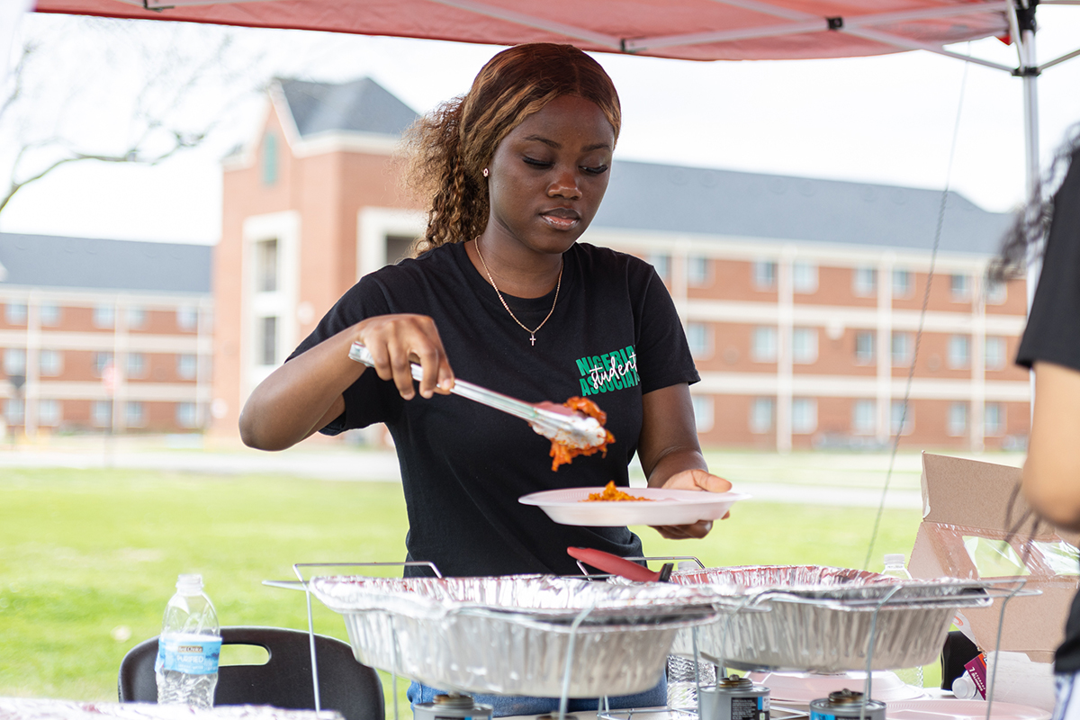 A Nigerian Student Association member gives out food to students at the Black History Month Block Party, Feb. 24, at Cardinal Park. UP photo by Brian Quijada.