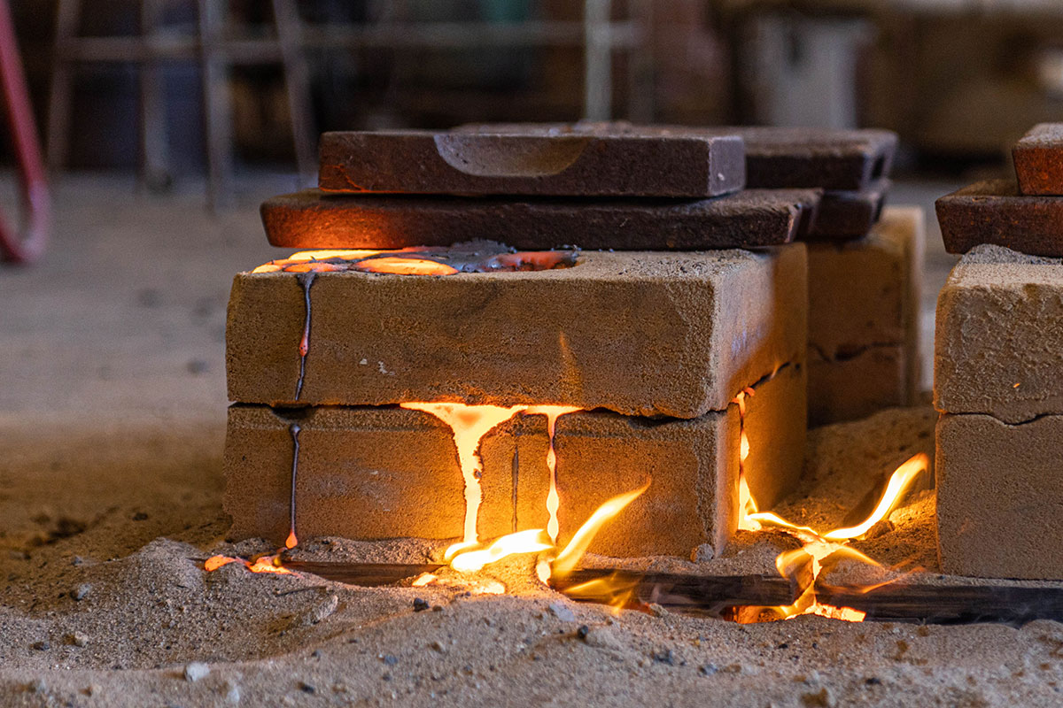 Molten iron spews out from the sides of the sand mold, March 3, at the art foundry. UP photo by Brian Quijada.