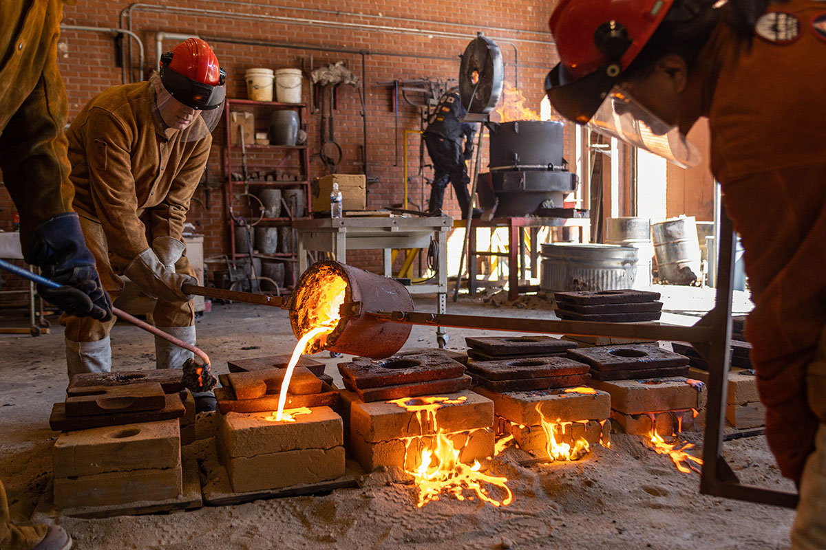 Instructors pour the molten iron into the sand molds as the other molds are on fire, March 3, at the art foundry. UP photo by Brian Quijada.