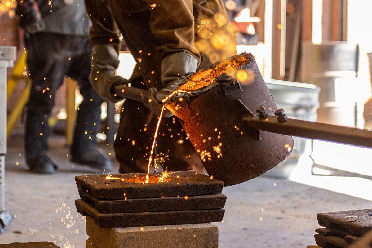 Sparks fly out as the molten iron is being poured into the sand mold, March 3, at the art foundry. UP photo by Brian Quijada.