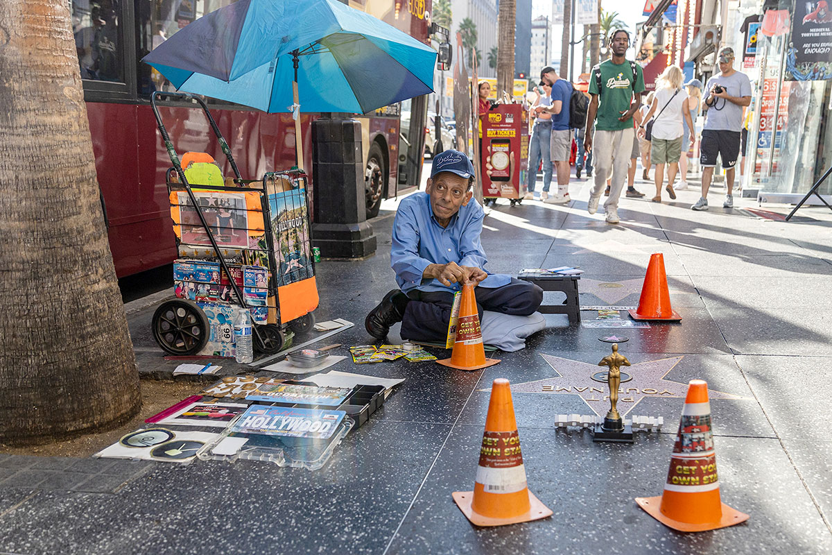 A man sits on the ground cutting up letters to put on stars for tourists on Hollywood Boulevard, Los Angeles, Oct. 6. UP photo by Brian Quijada.