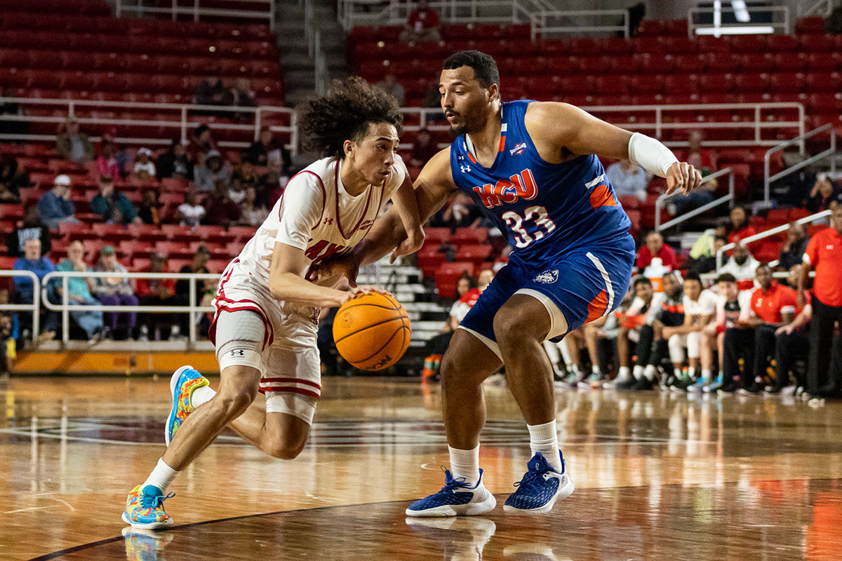 Cardinal guard Nate Calmese dribbles past HCU defender to score the basket, Feb. 16, at the Montagne Center. UP image by Brian Quijada.