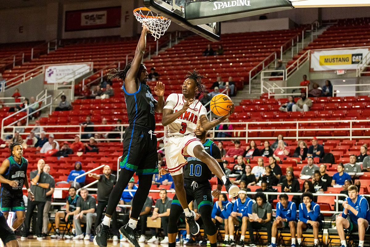 Sophomore guard Jakevion Buckley passes the ball under the basket to avoid a foul from Texas A&M-Corpus Christi defender, Jan 19, at the Montagne Center. UP image by Brian Quijada.