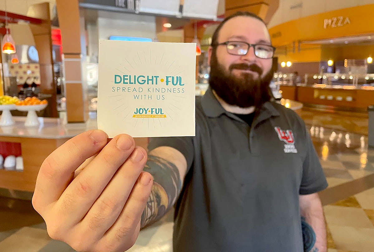 Dillon Tomlin, Chartwells front of house staffer in the Brooks-Shivers Dining Hall, holds a card promoting the "Delightful" event, set for Feb. 12. UP photo by E.J. McMillen