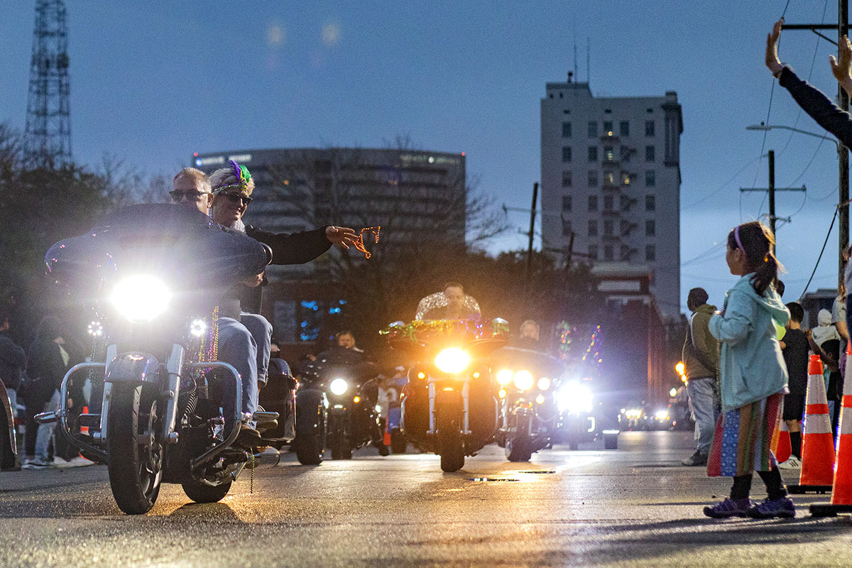 A woman riding a motorcycle throws beads to a little girl in the crowd during the Mardi Gras of Southeast Texas parade, in downtown Beaumont, Feb 10. UP photo by Brian Quijada.