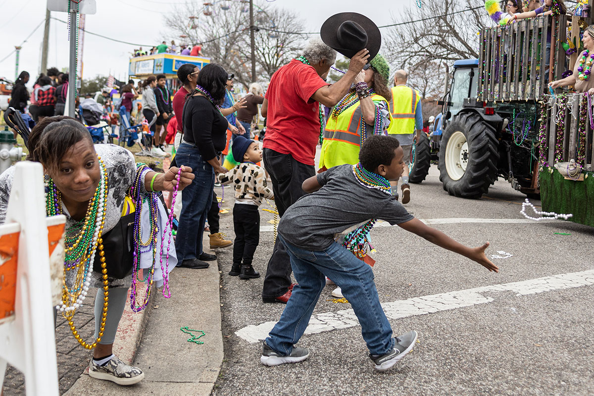 A son and mother collect beads from the floats during the Mardi Gras of Southeast Texas parade, in downtown Beaumont, Feb 11. UP photo by Brian Quijada.
