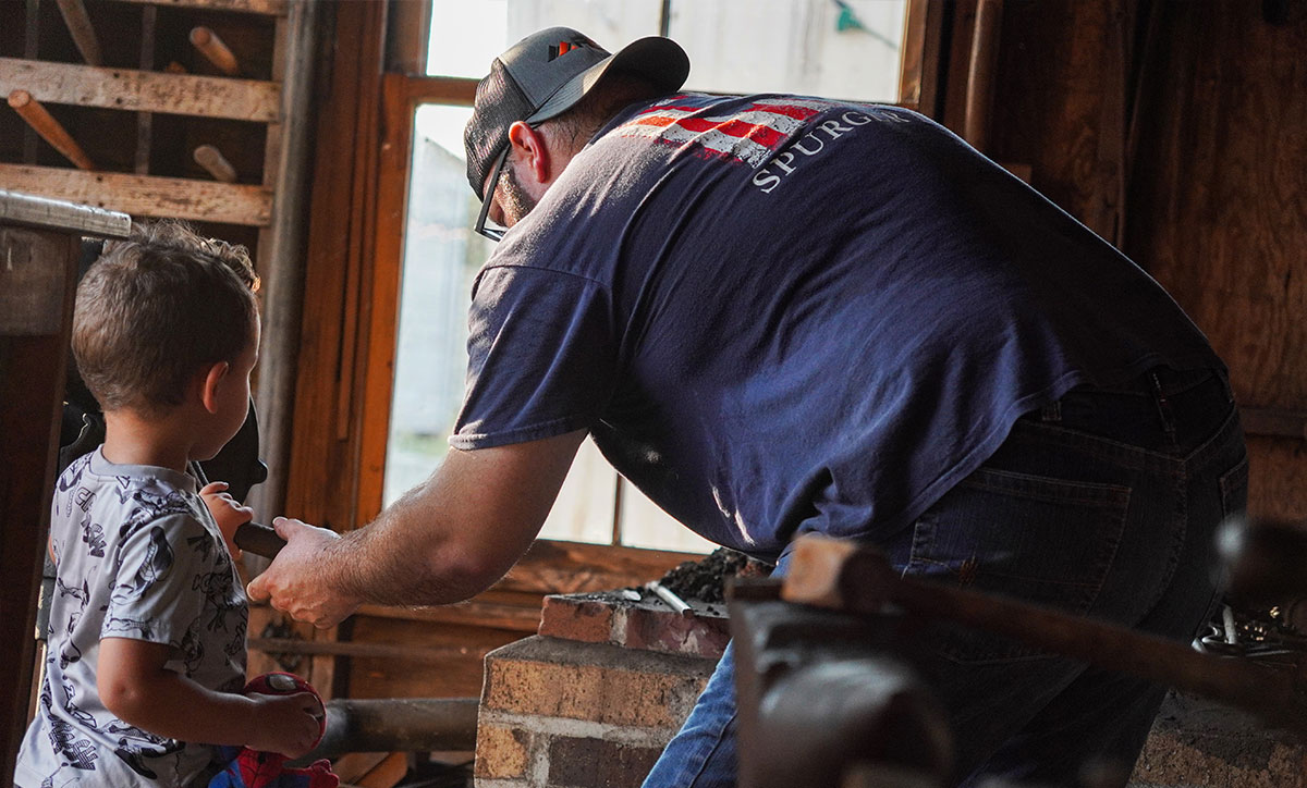Matt Horn showing a kid how the Forge works at the Southern Carriage Workshop in the Spindletop Gladys City Boomtown Museum, Aug. 22. UP Photo by Carlos Viloria