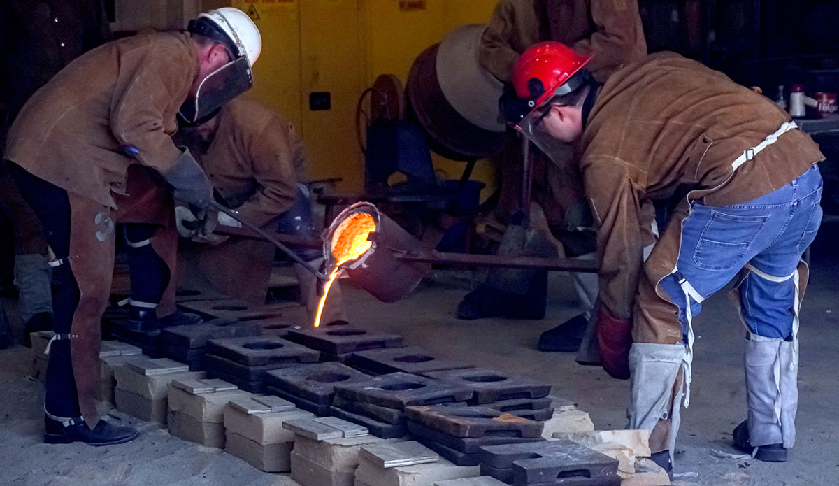 An Instructor and a student pour the molten iron into the sand molds, March 22, at the art foundry. UP photo by Carlos Viloria.