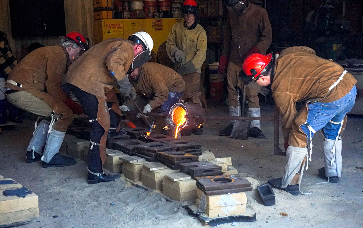 An Instructor and a student pour the molten iron into the sand molds, March 22, at the art foundry. UP photo by Carlos Viloria.