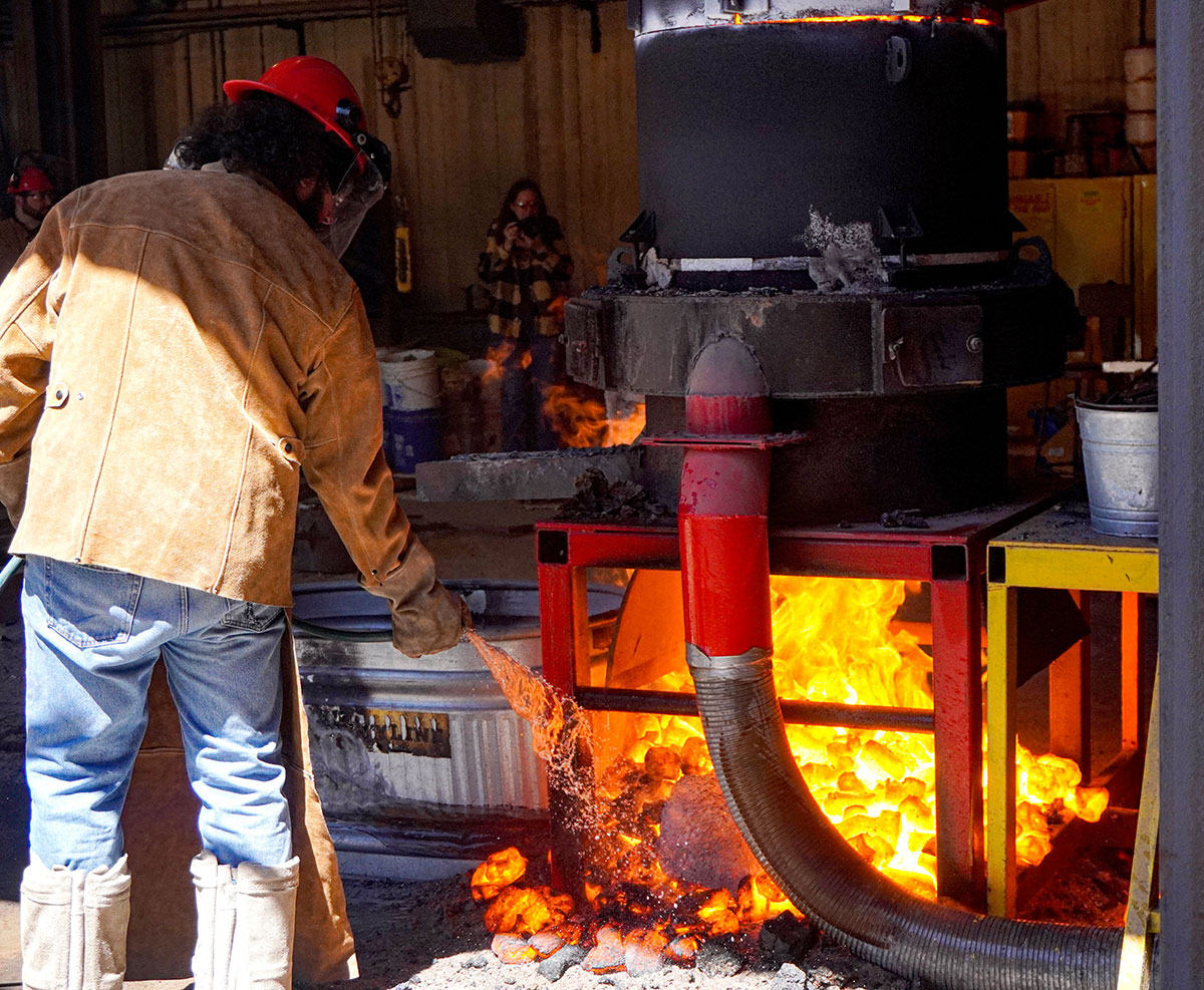 LU student Allan Cantu uses a water hose to extinguish the fire under the cupula furnace, March 22, at the art foundry. UP photo by Carlos Viloria.